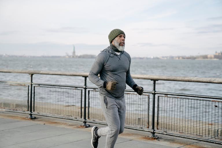 Mature man in activewear running and walking by the waterfront, promoting healthy lifestyle and wellness.