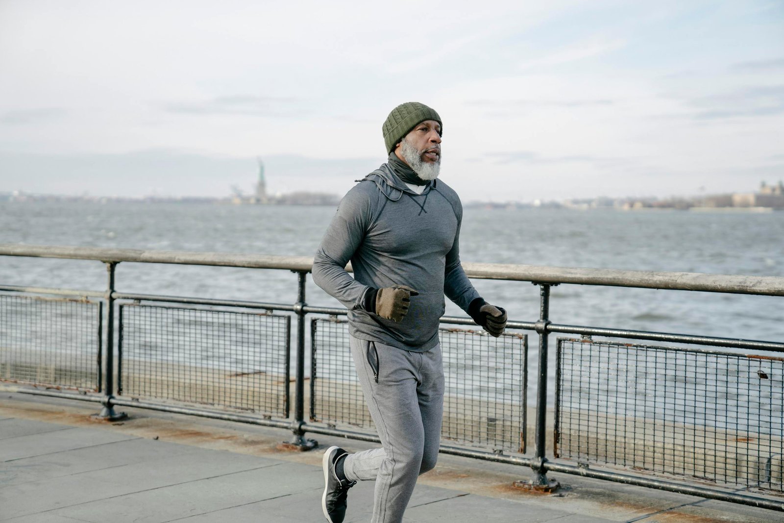 Mature man in activewear running and walking by the waterfront, promoting healthy lifestyle and wellness.
